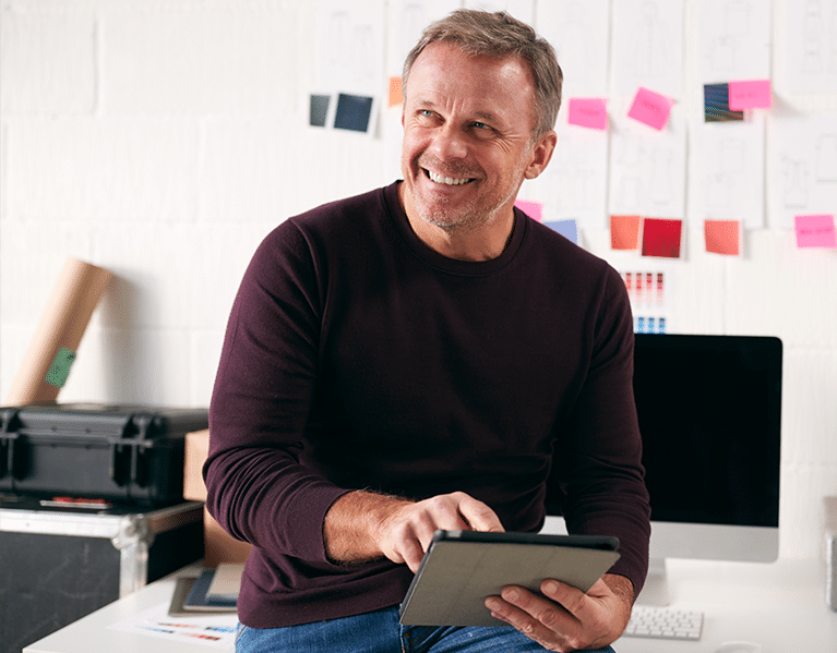 Smiling business owner works on tablet in office